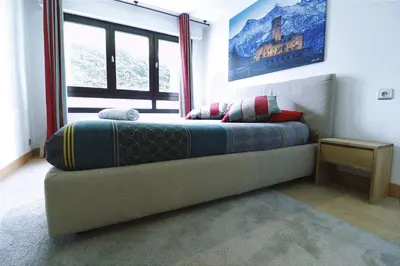 a bedroom with a bed with a painting on the wall at Cozy Alpine Stay Séjour cosy au centre in Chamonix-Mont-Blanc