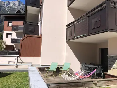 a group of chairs and tables on a balcony at Cozy Alpine Stay Séjour cosy au centre in Chamonix-Mont-Blanc