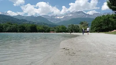 two people walking on a beach near a body of water at Cozy Alpine Stay Séjour cosy au centre in Chamonix-Mont-Blanc