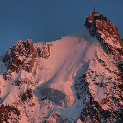 a snow covered mountain with a house on top of it at Cozy Alpine Stay Séjour cosy au centre in Chamonix-Mont-Blanc