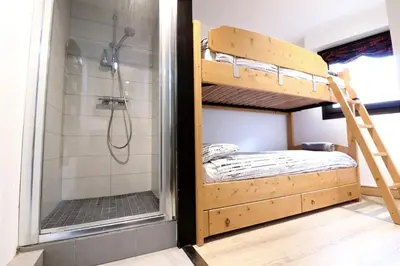a bedroom with a bunk bed and a shower at Cozy Alpine Stay Séjour cosy au centre in Chamonix-Mont-Blanc