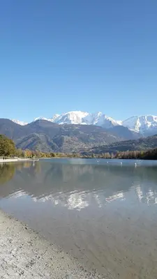 a large lake with snow covered mountains in the background at A Cordon entre Bois et Nature in Cordon