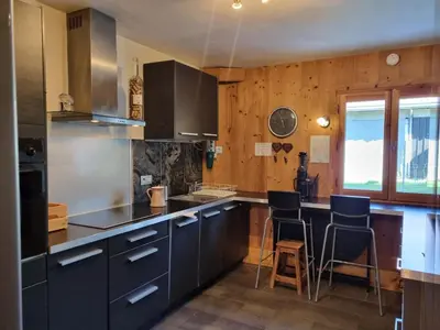 a kitchen with black cabinets and a counter with stools at A Cordon entre Bois et Nature in Cordon