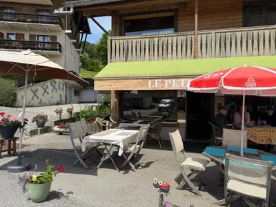 an outdoor patio with tables and chairs and umbrellas at A Cordon entre Bois et Nature in Cordon