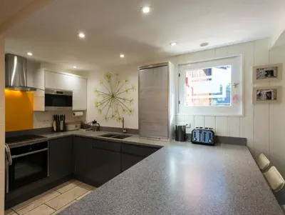 a kitchen with black cabinets and a large window at Ski-in/ski-out & pool: great for summer and winter in Saint-Gervais-les-Bains