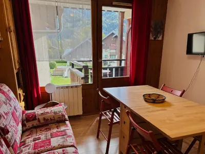 a living room with a table and a couch at Studio cosy centre village, animaux acceptés, parking privé - FR-1-624-121 in Samoëns