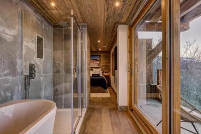 a bathroom with a tub and a bedroom at Chalet Chèvrefeuille in Saint-Gervais-les-Bains