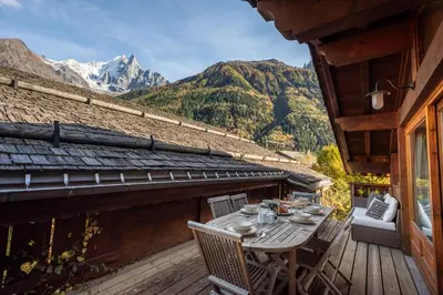 a table on a deck with a view of mountains at Chalet Kaiya - Alpes Travel - Les Praz - sleeps 8 in Chamonix-Mont-Blanc
