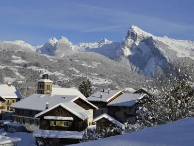 a building covered in snow with mountains in the background at Charmant T3 Neuf, Skibus Gratuit, Terrasse, 2 Places Privées, WIFI - Samoëns - FR-1-624-122 in Samoëns