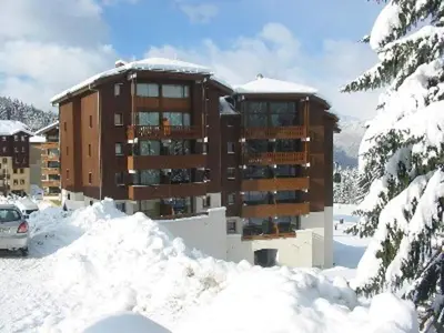 a large building with snow covered mountains in the background at 3 Pièces au pied des pistes pour 4 personnes à Morillon - FR-1-815-84 in Morillon