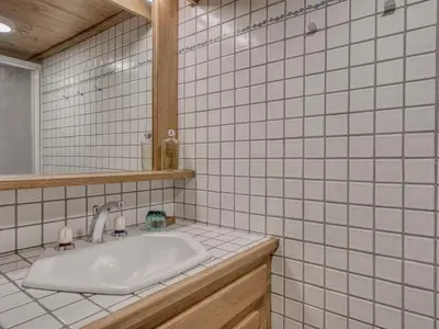 a white tiled bathroom with a sink and a mirror at Charmant appartement 2 chambres à Megève avec Wifi et parking - FR-1-453-292 in Megève