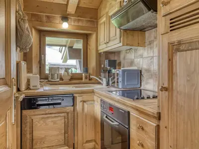 a kitchen with wooden cabinets and a stove at Charmant appartement 2 chambres à Megève avec Wifi et parking - FR-1-453-292 in Megève