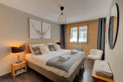 a bedroom with a large bed and a chair at Apartment Aiguille de Chamonix- Alpes Travel - Central Chamonix (sleeps 4) in Chamonix-Mont-Blanc