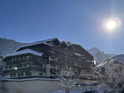 a building covered in snow with the sun behind it at Studio 4 pers avec balcon, proche pistes et commerces, centre village - FR-1-572-165 in Arâches-la-Frasse