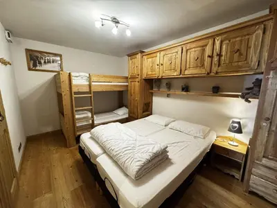 a bedroom with a bed and bunk beds with wooden cabinets at Appartement cosy 6 personnes avec garage, terrasse et wifi au cœur du village, proche pistes et commerces - FR-1-572-251 in Arâches-la-Frasse