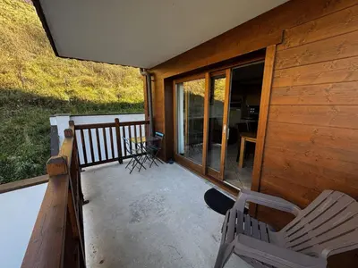 a porch of a cabin with two chairs and a table at Appartement cosy 6 personnes avec garage, terrasse et wifi au cœur du village, proche pistes et commerces - FR-1-572-251 in Arâches-la-Frasse