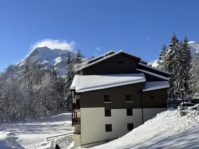 a building in the snow with a mountain in the background at Studio aux Carroz 4 pers, balcon, proche commerces et pistes - FR-1-572-254 in Arâches-la-Frasse