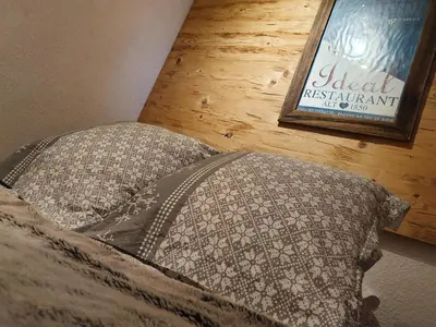 a bed with two pillows and a sign on a wall at Mountain RoomChaleureux - Accueillant & Convivial in Demi-Quartier