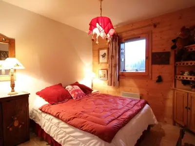 a bedroom with a bed with a red comforter and a window at Appartement 3 pièces pour 6 pers, bien équipé, face au spa et ski bus, proche pistes et commerces - FR-1-572-10 in Arâches-la-Frasse