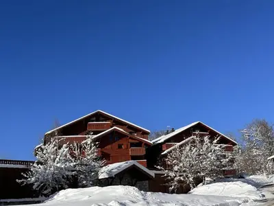 a log cabin in the snow with two trees at Appartement 3 pièces pour 6 pers, bien équipé, face au spa et ski bus, proche pistes et commerces - FR-1-572-10 in Arâches-la-Frasse