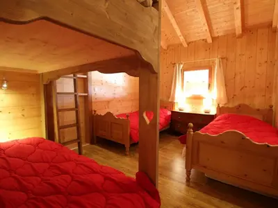 a bedroom with two beds in a log cabin at Chalet cosy 12 pers. à 1km des pistes, 5 ch., WiFi, cheminée, abri voiture - FR-1-572-30 in Arâches-la-Frasse