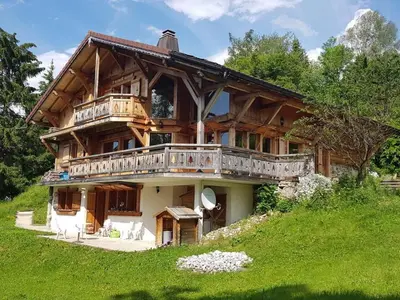 a large wooden house with a balcony on a hill at Chalet cosy 12 pers. à 1km des pistes, 5 ch., WiFi, cheminée, abri voiture - FR-1-572-30 in Arâches-la-Frasse