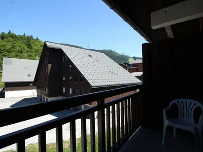 a balcony with a chair and a building at Charmant studio duplex rénové, 4/5 pers, garage, proche centre, pistes et commerces. - FR-1-572-60 in Arâches-la-Frasse