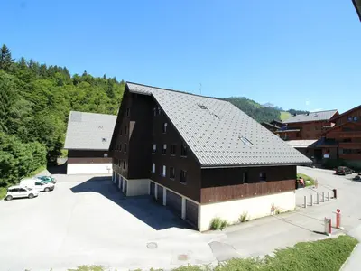 an aerial view of a black barn with a parking lot at Charmant studio duplex rénové, 4/5 pers, garage, proche centre, pistes et commerces. - FR-1-572-60 in Arâches-la-Frasse