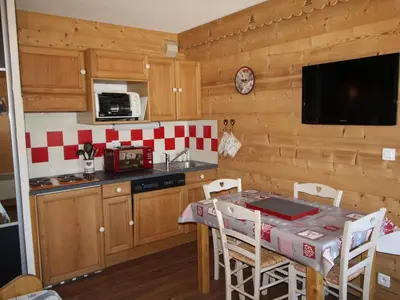 a kitchen with a table with chairs and a microwave at Appartement cosy 4 pers au pied des pistes avec parking, balcon, lave-vaisselle et services additionnels - FR-1-572-87 in Arâches-la-Frasse