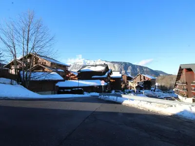 a snow covered town with a mountain in the background at Studio 4 pers. avec lave-linge, balcon et accès direct aux pistes - Proche centre des Carroz - FR-1-572-176 in Arâches-la-Frasse
