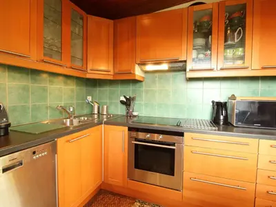 a kitchen with wooden cabinets and stainless steel appliances at Chalet 5 ch, 11 pers, terrasse sud, Les Carroz - FR-1-572-115 in Arâches-la-Frasse