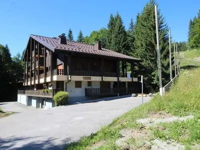 a house on a hill with trees in the background at Duplex 8 pers avec parking, pied des pistes, proche commodités - FR-1-572-127 in Arâches-la-Frasse