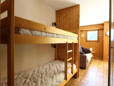a bedroom with two bunk beds and a couch at Appartement cosy 2 pièces, terrasse, pour 6 personnes au pied des pistes et proche du centre - FR-1-572-125 in Arâches-la-Frasse