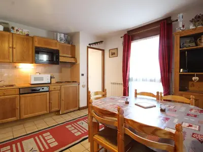 a kitchen with a dining room table and a kitchen with a microwave at Charmant 2P avec balcon, 5 couchages, pieds des pistes, proche télécabine et centre village - FR-1-572-171 in Arâches-la-Frasse