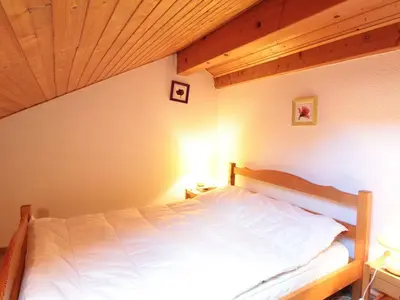 a bedroom with a white bed with a wooden ceiling at Studio mezzanine 5 pers, pied des commerces, 450m des pistes - FR-1-572-184 in Arâches-la-Frasse
