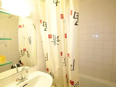 a bathroom with a sink and a shower curtain with writing at Studio mezzanine 5 pers, pied des commerces, 450m des pistes - FR-1-572-184 in Arâches-la-Frasse
