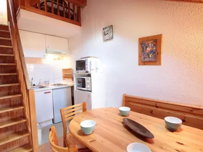 a kitchen with a wooden table and a kitchen with a refrigerator at Studio mezzanine 5 pers, pied des commerces, 450m des pistes - FR-1-572-184 in Arâches-la-Frasse