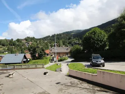 a car parked in a parking lot next to a mountain at Charmant appartement 4-6 pers, balcon, proche pistes et commodités - FR-1-572-142 in Arâches-la-Frasse