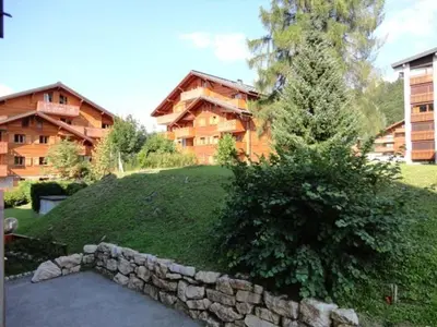 a house with a stone wall and a tree at Appartement rénové 2P 4 pers, proche pistes et commerces - FR-1-572-20 in Arâches-la-Frasse