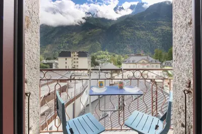 a table and chairs on a balcony with a view of a mountain at Nook 40 - Les Balances - Central Mont-Blanc views in Chamonix-Mont-Blanc