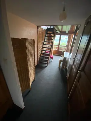 a hallway with a staircase and a chair and a window at Appartement face Mont Blanc in Demi-Quartier