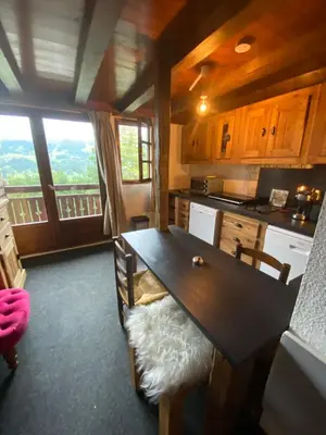 a kitchen with a table with chairs and a balcony at Appartement face Mont Blanc in Demi-Quartier