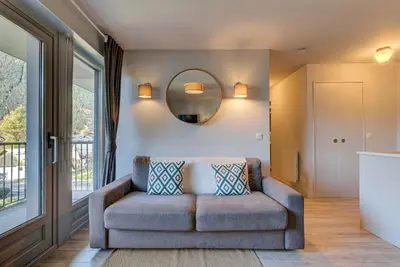 a living room with a couch and a mirror at Apartment Fermes du Montenvers B2- Alpes Travel - Central Chamonix (sleeps 4-5) in Chamonix-Mont-Blanc