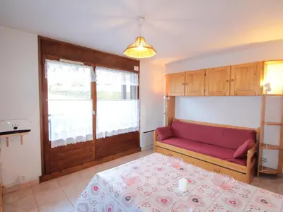 a bedroom with a bed and a red couch at Studio central village aux Carroz, animaux admis, 5 pers - FR-1-572-202 in Arâches-la-Frasse