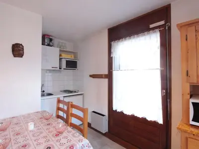 a small kitchen with a table and a door at Studio central village aux Carroz, animaux admis, 5 pers - FR-1-572-202 in Arâches-la-Frasse