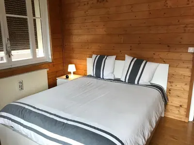 a bedroom with a bed with a wooden wall at Chambres à Sallanches in Sallanches