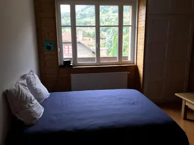 a bedroom with a blue bed with a large window at Chambres à Sallanches in Sallanches