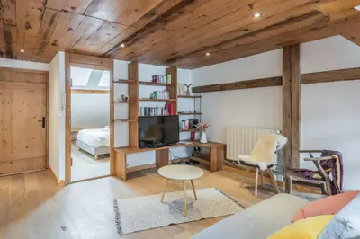 a living room with wooden ceilings and a bedroom at Appartement Soffitta - Welkeys in Chamonix-Mont-Blanc