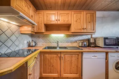 a kitchen with wooden cabinets and a sink at Chalet Nessa in Combloux