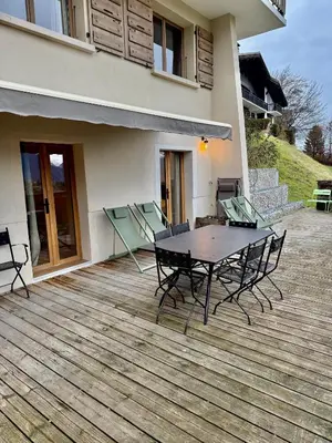 a wooden deck with a table and chairs on a house at Chalet Nessa in Combloux